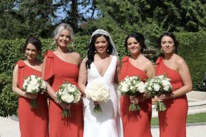Bride and bridesmaids in red one shoulder dress with bow
